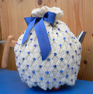 Beaded Beauty theemuts met blauw lint en kraaltjes.
