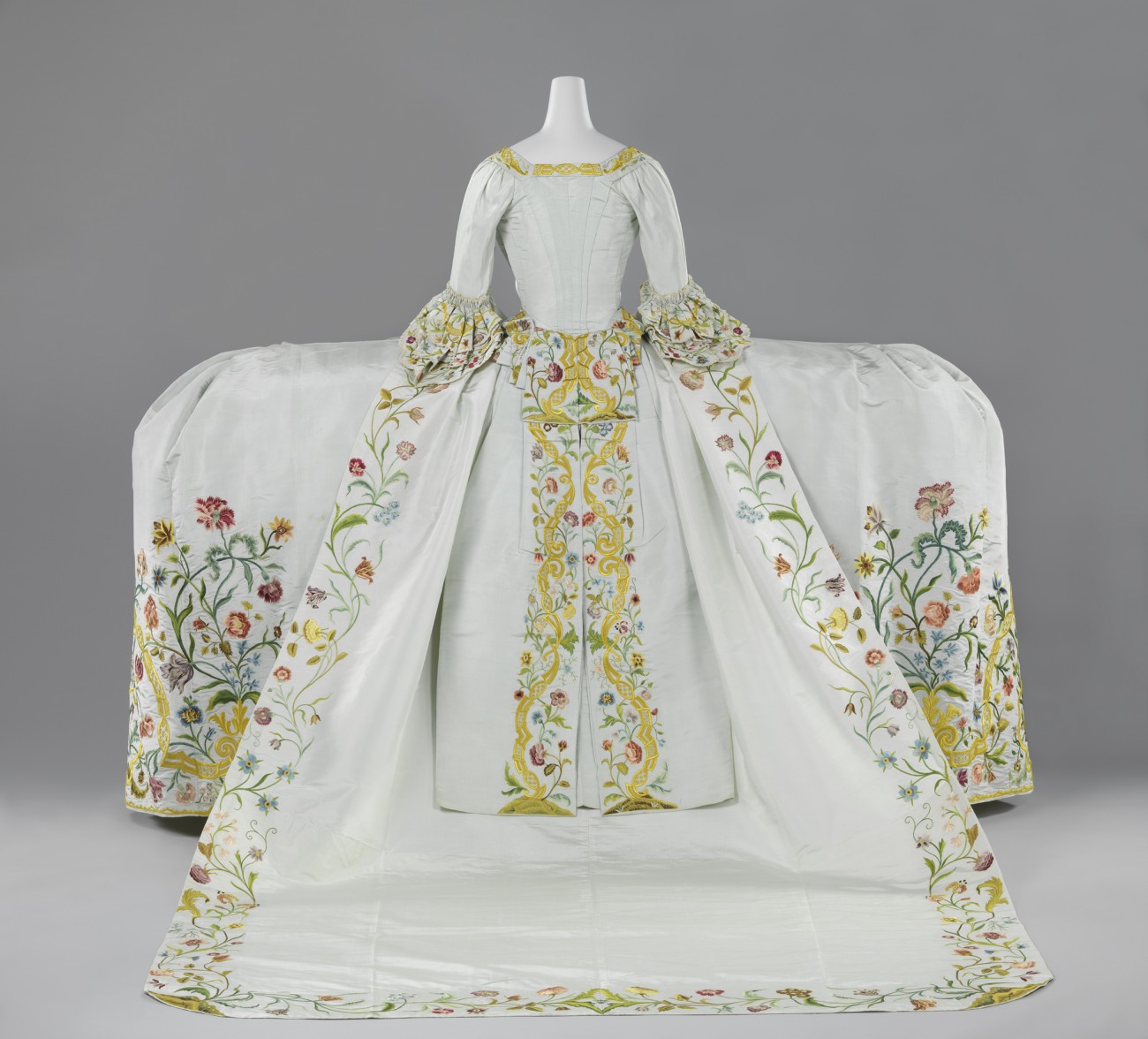 Trouwjapon van lichtblauwe ripszijde geborduurd met een floraal motief in veelkleurige zijde bestaande uit een lijf met staart, rok en sleep, circa 1750 - 1760.