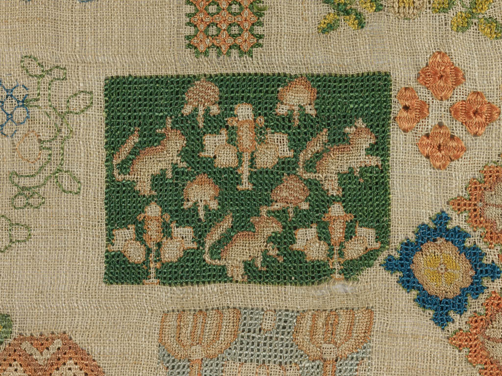 Detail van een ‘spot motif sampler’ uit de 17de eeuw. Linnen, geborduurd met veelkleurige zijde in verschillende steken, 21 x 52 cm.